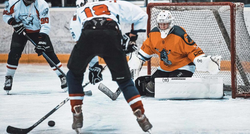 An ice hockey goalie prepares to stop a shot by an opposing player