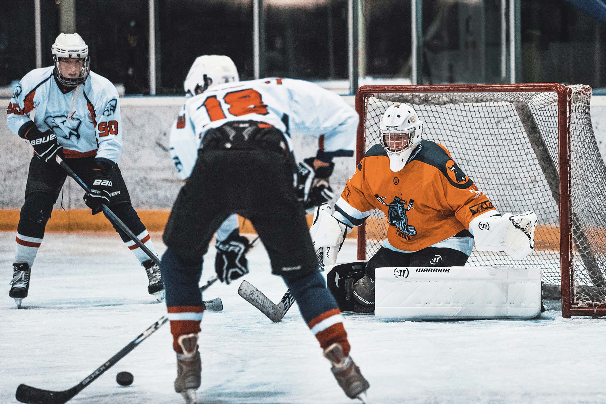 An ice hockey goalie prepares to stop a shot by an opposing player